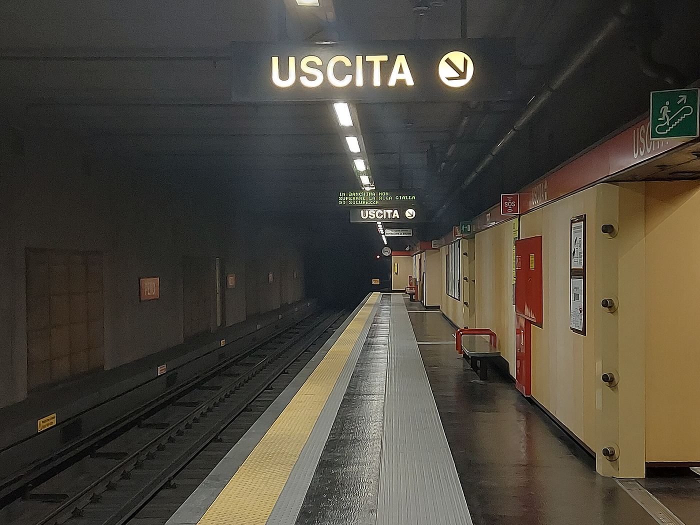 La banchina della stazione Pero della M1, con le scritte Uscita illuminate e la linea gialla di sicurezza
